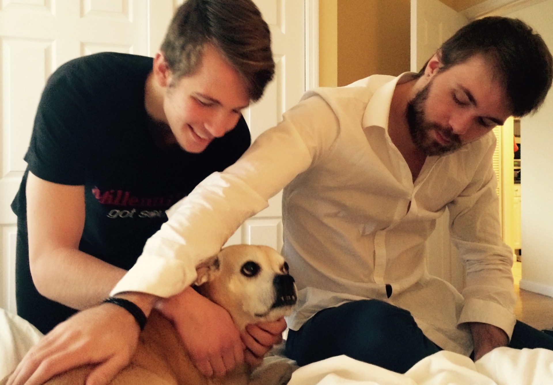 Two young men petting dog.