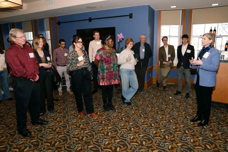 People standing listening to speaker in casual professional setting. 